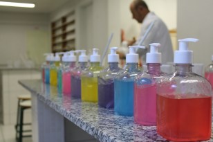 Imagem que mostra uma bancada de um laboratório de Química. Nela estão dispostos lado a lado vários recipientes contendo líquidos coloridos.