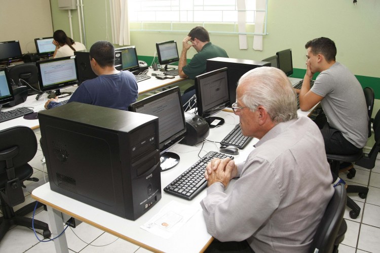 Foto de estudantes de diferentes idades em laboratório de informátia da EJA.